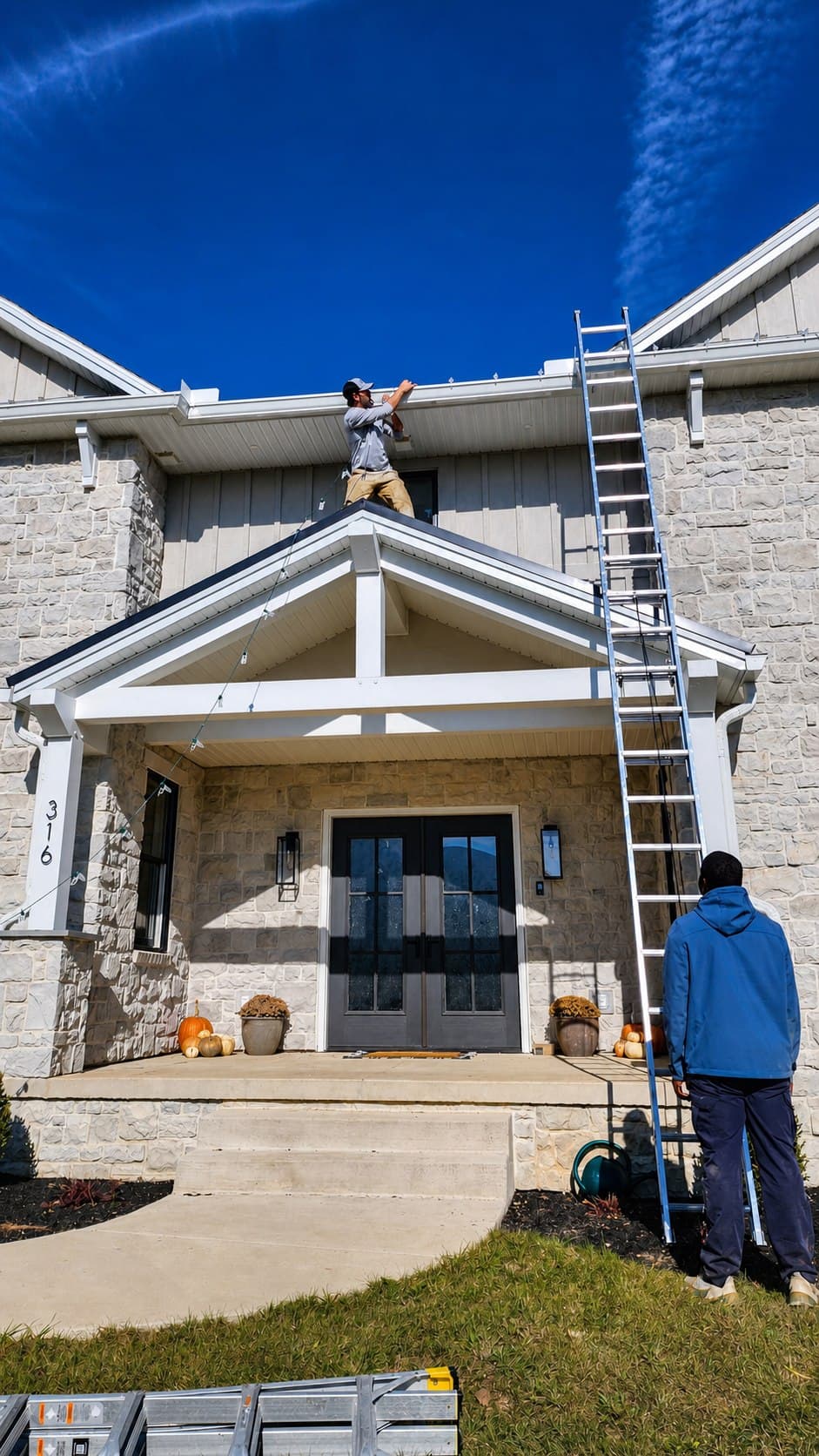 Penn Holiday Lights installer fitting C9 roofline lights from an extension ladder in Mechanicsburg, Pennsylvania